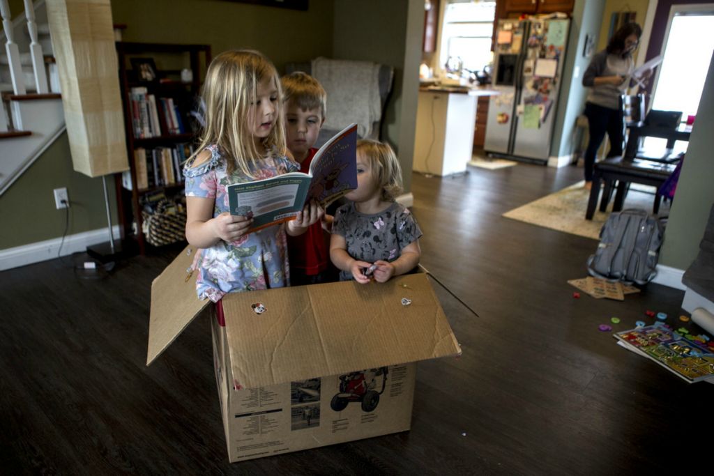 Award of Excellence, Feature - Jessica Phelps / Newark Advocate, “Learning From Home”Lily Morgan, 6, reads to her brother Isaac, 5, in a box their parents saved for them to use while they are home from school due to the novel coronavirus. This is the first week of school closures in Ohio and parents have been scrambling for ways to homeschool their children and keep them engaged in learning. Isaac was fulfilling one of his school requirements by having a family member read to him. In the background their mom, Liz Morgan is busy clearing the table from the mornings first round of lessons. 